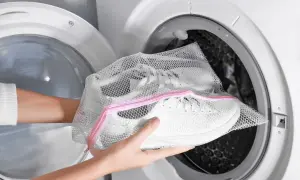 Mani inseriscono scarpe bianche in una retina per lavatrice, un modo semplice per capire come lavare le scarpe in lavatrice.