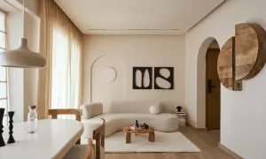Soggiorno in stile minimalista con divano curvo, tavolino in legno e decorazioni astratte.