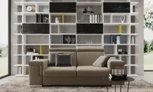 Divano moderno in un soggiorno ampio, con libreria bianca a giorno piena di libri e oggetti d'arte.