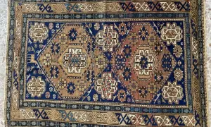 Tappeti Shirvan con motivi geometrici esagonali e floreali su sfondo blu e marrone. Bordi decorati con motivi a zig-zag.
