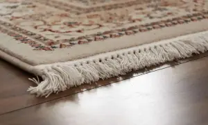 Dettaglio di un tappeto con frange bianche su parquet lucido. Scopri come pulire i tappeti per mantenerli splendenti.