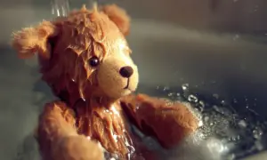 Orsetto di peluche bagnato, con gocce d'acqua che scendono. Una scena che ricorda come lavare i peluche in lavatrice per farli tornare come nuovi.