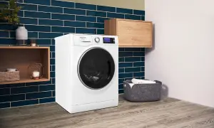 Lavatrice Hotpoint con funzione Steam Care, che significa cura delicata dei tessuti. Ambiente moderno con dettagli in legno e piastrelle blu.