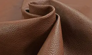 Tessuto di pelle pieno fiore marrone, con una texture granulosa che ne esalta il significato di qualità e naturalezza.