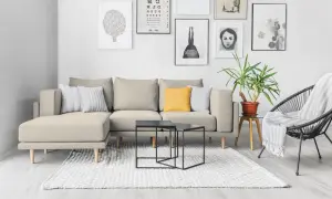 Divano componibile beige con cuscini decorativi, tavolini neri e poltrona nera. Idee su come rivestire un divano non sfoderabile.