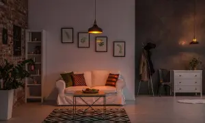 Soggiorno accogliente con divano bianco, tappeto geometrico e lampade che creano un'atmosfera calda, perfetti colori per stanze poco luminose.