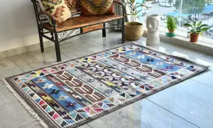 Tappeto kilim colorato con motivi geometrici. Il suo significato è legato alla tradizione tessile, un'arte che racconta storie attraverso i disegni.