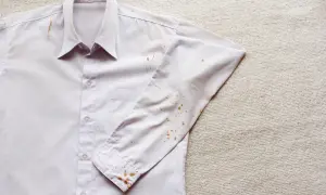 Camicia bianca con macchie di ruggine vecchie sui tessuti, soprattutto sulla manica e sul colletto.