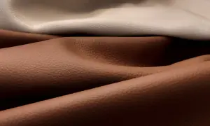 Pieghe morbide di pelle pigmentata in tonalità sabbia e cuoio, con texture granulosa visibile.