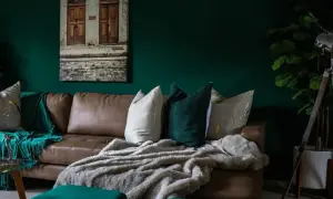 Divano in pelle marrone con cuscini decorativi e coperte morbide, che creano un'atmosfera accogliente. Diversi tipi di pelle e tessuto si combinano per un look sofisticato.