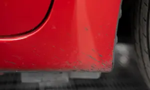 Macchie scure sulla carrozzeria rossa di un'auto, un problema comune per chi cerca come togliere le macchie di catrame.