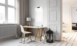 Scrivania con sedia bianca e lampada, accanto a un termosifone. Idee per come arredare parete con termosifone, con decorazioni minimaliste.