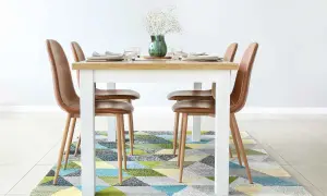 Tappeto sotto il tavolo da pranzo: sì! Un tappeto geometrico colorato aggiunge stile e comfort alla zona pranzo con sedie in pelle marrone.