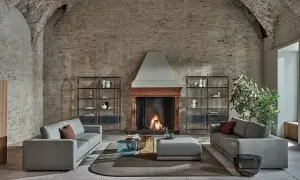 Scegliere tappeto salotto: un'elegante zona living con divani grigi, camino acceso e tavolini moderni su un tappeto rotondo.