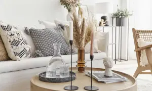 Un accogliente salotto bohemien con cuscini decorati, un vaso di erba della pampa e un tavolino con oggetti d'arte.