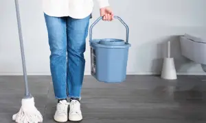 Persona con secchiello e straccio per capire come lavare gli stracci del pavimento.