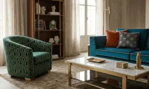 Poltrona verde con motivo geometrico dorato, che ricorda come si fa il velluto. Divano blu, tavolino in marmo e libreria completano l'arredamento.