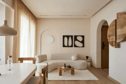 Soggiorno in stile minimalista con divano curvo, tavolino in legno e decorazioni astratte.