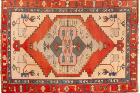 Tappeto turco con motivi geometrici e stilizzati di animali e alberi in colori vivaci.
