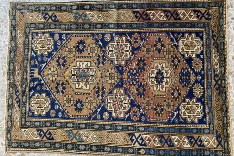 Tappeti Shirvan con motivi geometrici esagonali e floreali su sfondo blu e marrone. Bordi decorati con motivi a zig-zag.