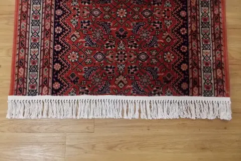 Tappeto persiano rosso con frange bianche, pronto per la pulizia tappeti persiani con bicarbonato per un tocco di freschezza.