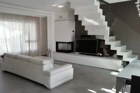 Soggiorno moderno con divano bianco, camino, TV e una scenografica scala a vista bianca. Ottime idee arredare soggiorno con scala a vista.