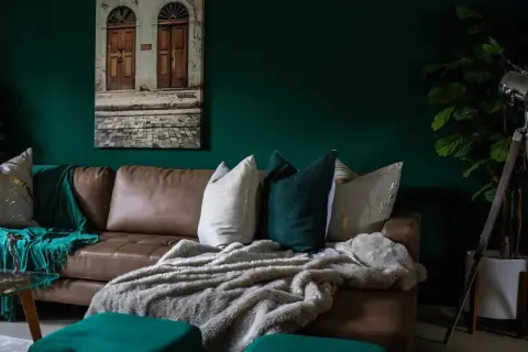 Divano in pelle marrone con cuscini decorativi e coperte morbide, che creano un'atmosfera accogliente. Diversi tipi di pelle e tessuto si combinano per un look sofisticato.