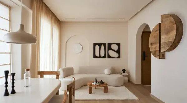 Soggiorno in stile minimalista con divano curvo, tavolino in legno e decorazioni astratte.