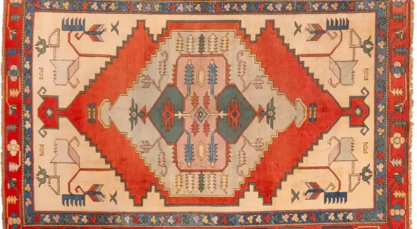 Tappeto turco con motivi geometrici e stilizzati di animali e alberi in colori vivaci.