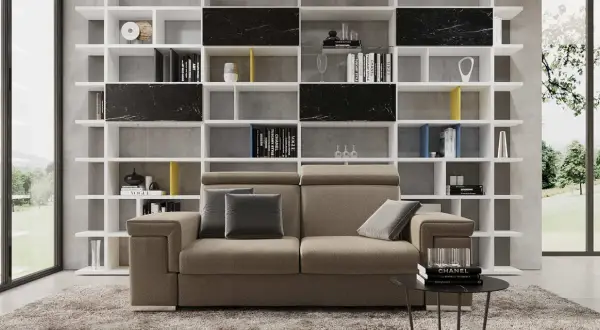 Divano moderno in un soggiorno ampio, con libreria bianca a giorno piena di libri e oggetti d'arte.