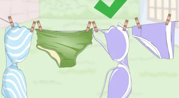 Biancheria intima appesa ad asciugare dopo il lavaggio in lavatrice. Un segno di spunta verde indica che è stato fatto correttamente.