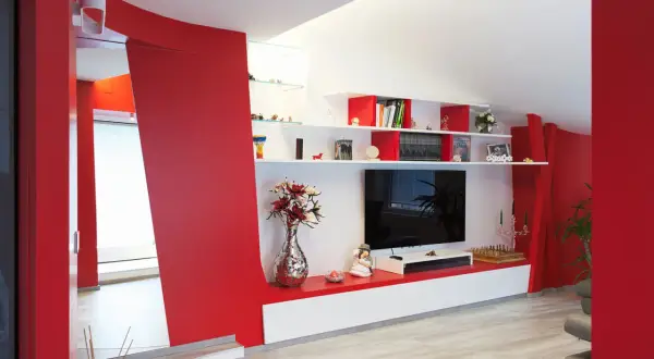 Pareti soggiorno rosso e grigio con mobile TV, libreria e decorazioni.
