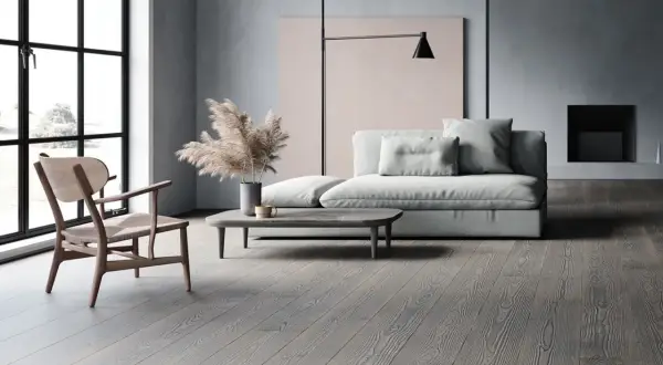 Soggiorno moderno con divano grigio chiaro, un tavolino e un pavimento in legno grigio.