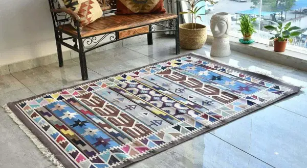 Tappeto kilim colorato con motivi geometrici. Il suo significato è legato alla tradizione tessile, un'arte che racconta storie attraverso i disegni.