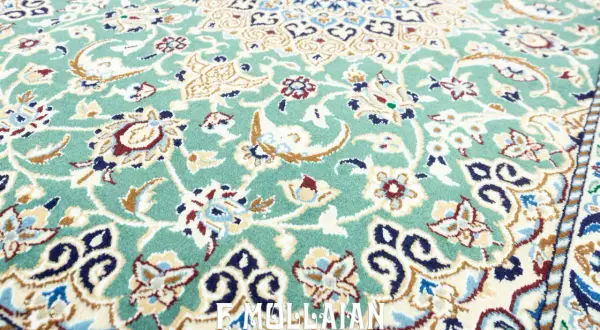 Un raffinato tappeto persiano verde, con intricati motivi floreali e un bordo decorato, evoca un'eleganza senza tempo.
