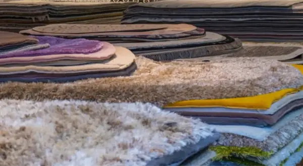 Pile di tappeti morbidi e colorati, tra cui un tappeto seta che brilla.