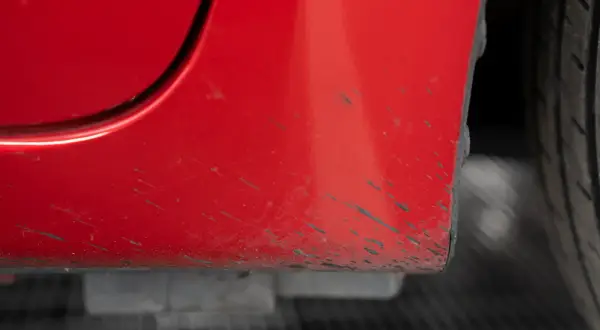 Macchie scure sulla carrozzeria rossa di un'auto, un problema comune per chi cerca come togliere le macchie di catrame.