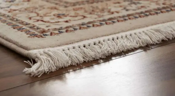 Dettaglio di un tappeto persiano con frange bianche, pronto per la pulizia professionale per mantenerne la bellezza.
