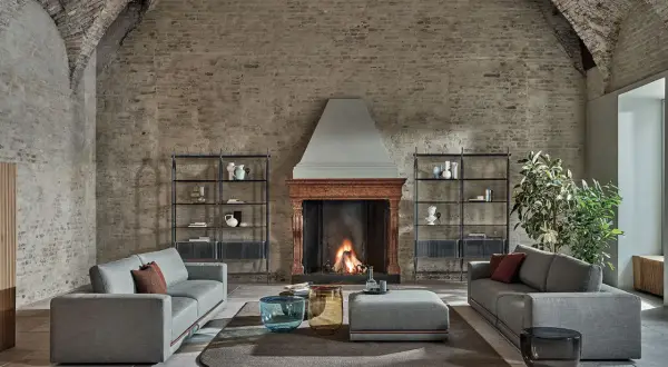 Scegliere tappeto salotto: un'elegante zona living con divani grigi, camino acceso e tavolini moderni su un tappeto rotondo.