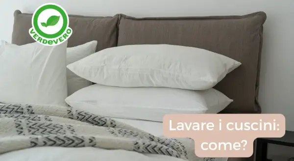 Bianchi cuscini su un letto, pronti per essere lavati in lavatrice. Scopri come lavare i cuscini per un sonno fresco e igienico.