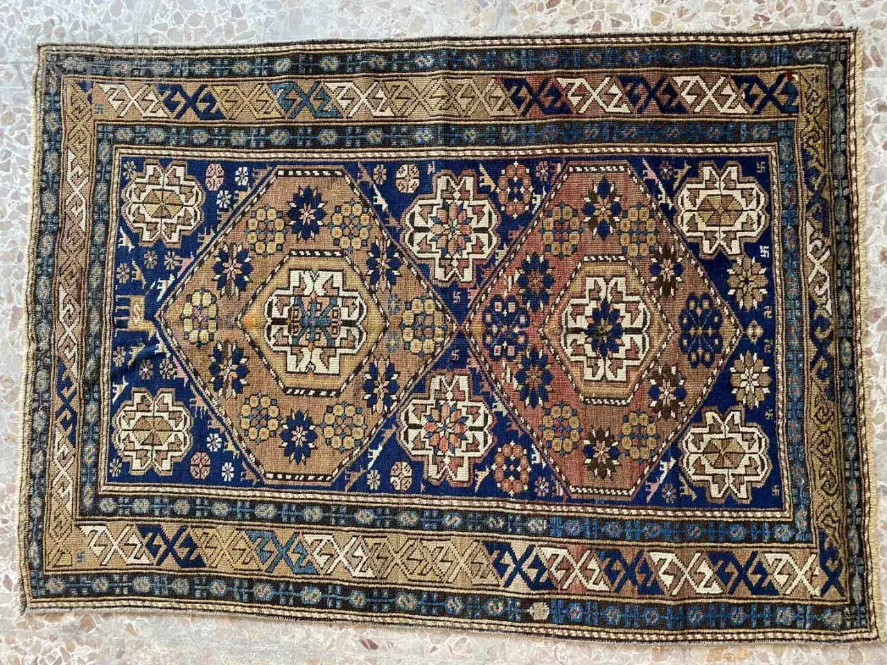 Tappeti Shirvan con motivi geometrici esagonali e floreali su sfondo blu e marrone. Bordi decorati con motivi a zig-zag.