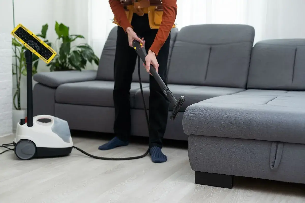 Pulizia profonda del divano Poltronesofà con un pulitore a vapore. Un professionista usa l'accessorio per igienizzare il tessuto.