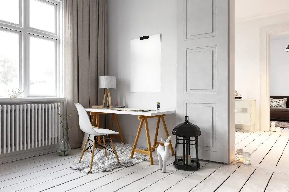Scrivania con sedia bianca e lampada, accanto a un termosifone. Idee per come arredare parete con termosifone, con decorazioni minimaliste.