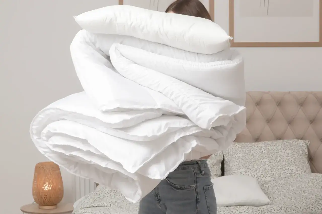 Donna con una trapunta nuova da lavare, piegata in un letto.