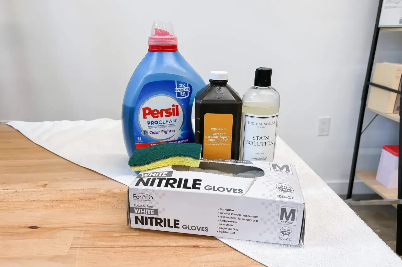 Kit per rimuovere macchie di sangue dai tessuti: detersivo, acqua ossigenata, smacchiatore, guanti in nitrile e spugna.