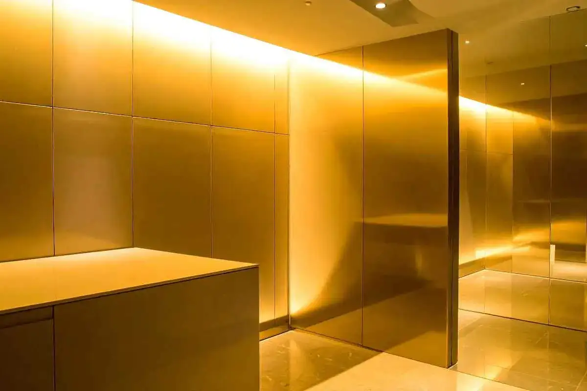 Un corridoio moderno con pareti e soffitto di un caldo color golden yellow, illuminate da luci a LED nascoste.