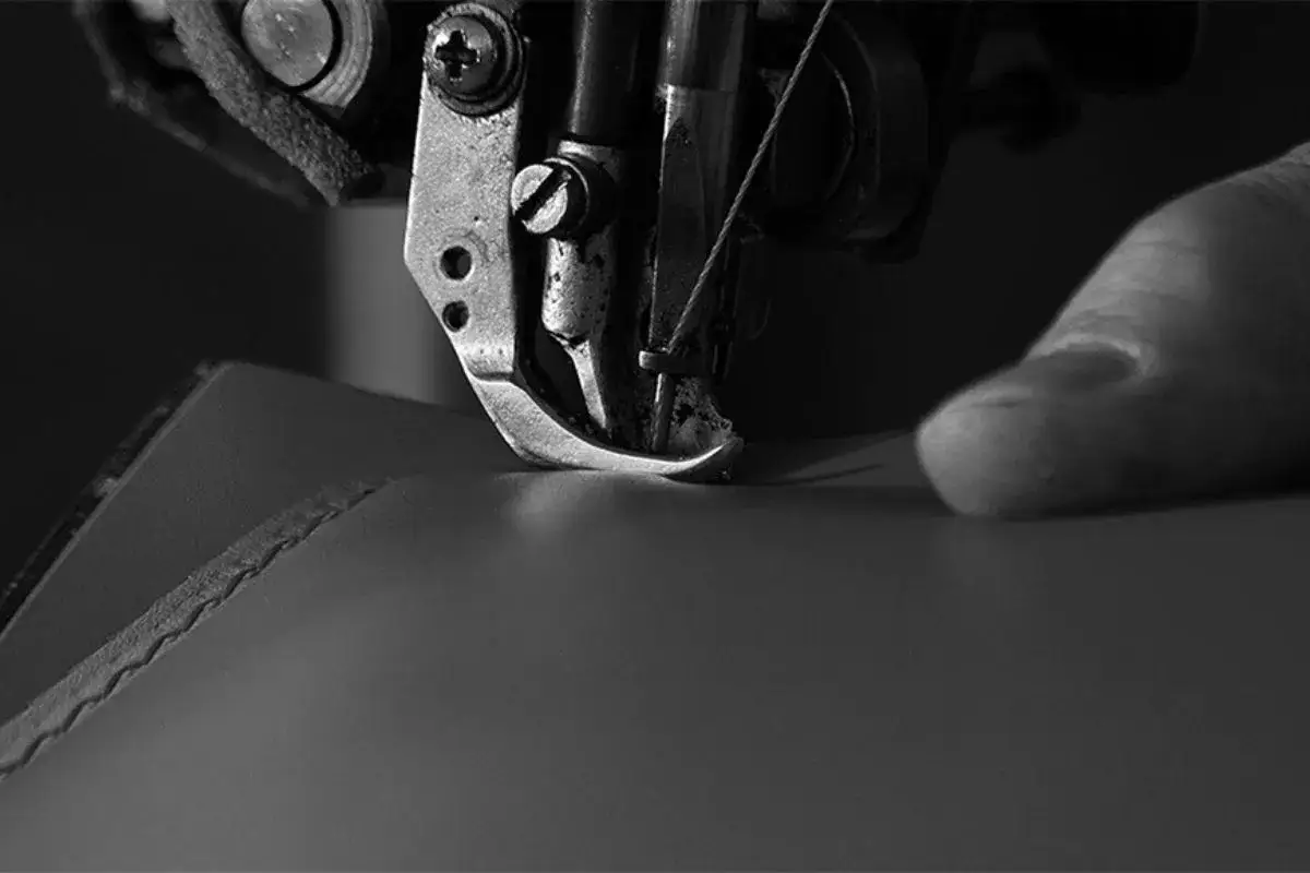 Macchina da cucire industriale che lavora su un pezzo di pelle, mostrando la cura artigianale e cos'è la pelle: un materiale resistente e versatile.