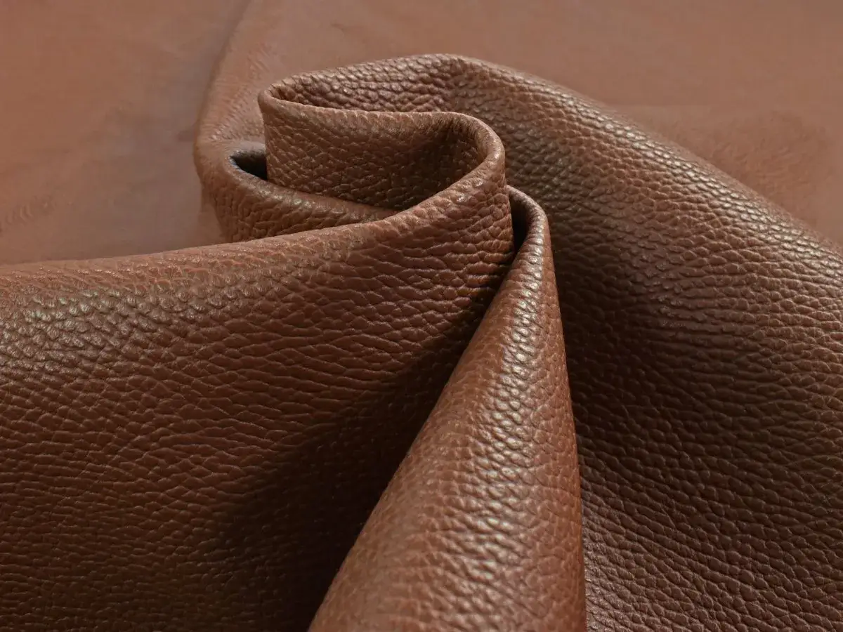 Tessuto di pelle pieno fiore marrone, con una texture granulosa che ne esalta il significato di qualit&agrave; e naturalezza.