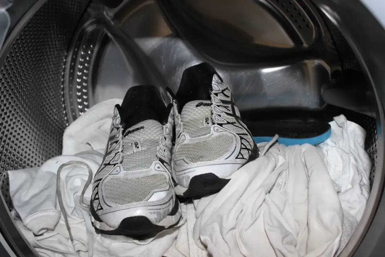 Scarpe da ginnastica pronte per essere lavate in lavatrice, con asciugamani bianchi per proteggerle. Ecco come lavare le scarpe in lavatrice per farle tornare come nuove.