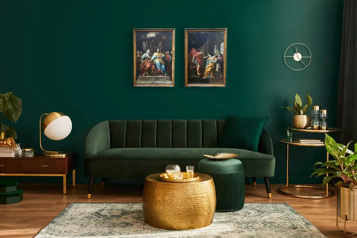 Elegante soggiorno con divano verde, tavolini dorati e due quadri classici che creano un contrasto moderno.